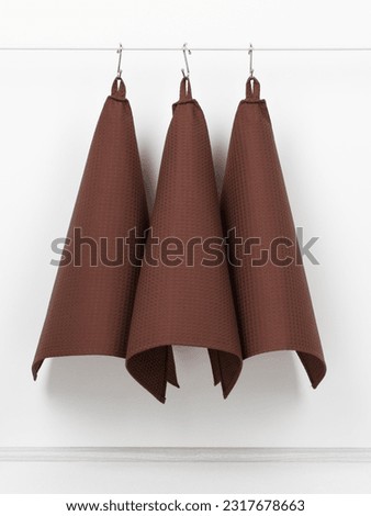 cotton waffle towels for the kitchen hang on hooks on a bracket against a white wall background