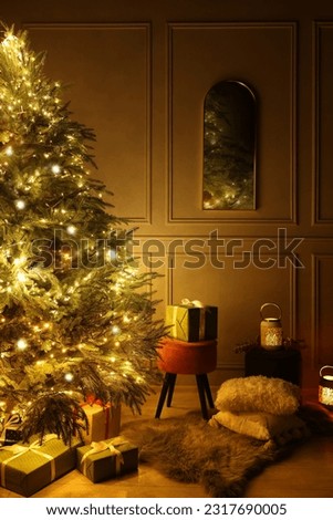 Beautiful Christmas tree decorated with festive lights and many gift boxes in room