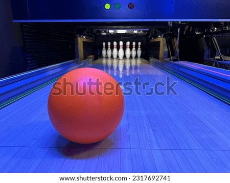 Skittles and bowling ball, blurred background. Red ball on the background of skittles. Game club, bowling set.