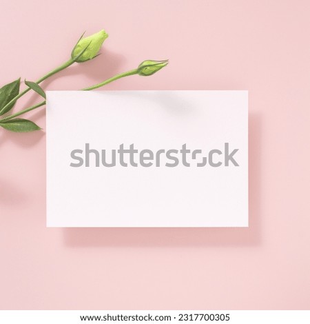 White paper empty blank, flowers decoration on pink background. White Invitation card mockup. Flat lay, top view, copy space, mockup