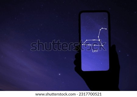 Woman using stargazing app on her phone at night, closeup. Identified stick figure pattern of Lion (Leo) constellation on device screen