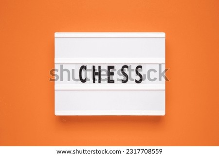 The word chess on lightbox isolated orange background. Education. Sport. Chess school. Design element.