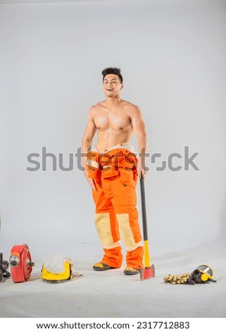 Topless firefighter using the iron axe supporting the ground on white background with smile.