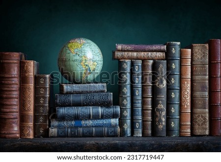 Old geographical globe and old book in cabinet with bookselfs. Science, education, travel background. History and geography team. Ancience, antique globe on the background of books. Royalty-Free Stock Photo #2317719447