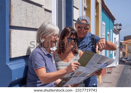 Happy group of traveler senior people looking at city map during a leisure trip in La Palma, Canary islands, enjoying a sunny day and healthy lifestyle Royalty-Free Stock Photo #2317719741