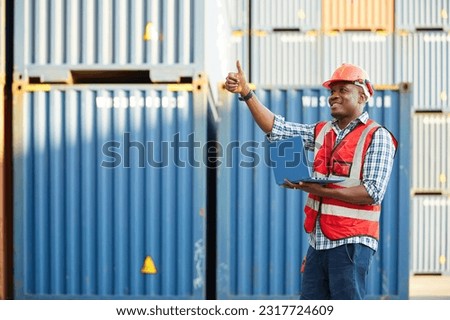 African factory worker or engineer working on laptop computer and thumbs up pose in containers warehouse storage