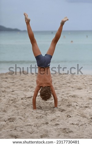 Little boy on the beach doing a handstand