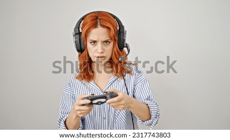 Young redhead woman playing video game over isolated white background