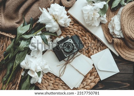 retro photo camera with book and fresh pink peony flowers.