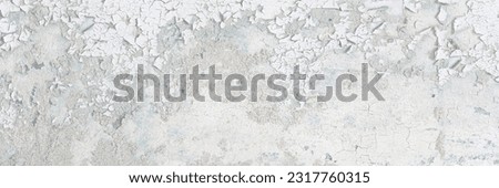 Peeling paint on the wall. Old concrete wall with cracked flaking paint. Weathered rough painted surface with patterns of cracks and peeling. Grunge texture for background and design. High resolution. Royalty-Free Stock Photo #2317760315