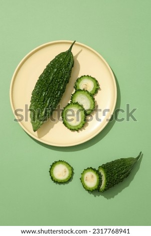 A bitter melon with three round slices arranged on a pastel dish. Bitter melon (Momordica charantia) has strong antioxidants, Vitamin A and Vitamin C which prevents skin aging Royalty-Free Stock Photo #2317768941