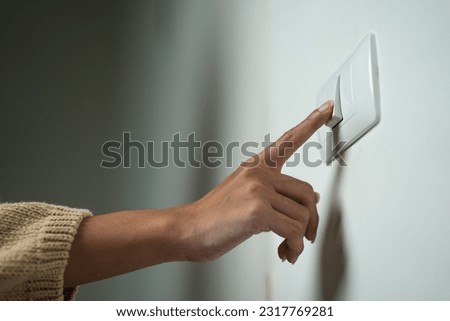 Earth Hour Close up woman finger turn off or on the light to saving electrical energy. Finger pushing light switch turn on or off. White switch Royalty-Free Stock Photo #2317769281