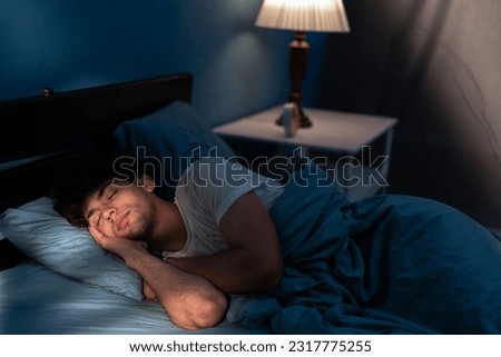 Peaceful young man sleeping in a comfortable bed alone at home, enjoying his orthopedic mattress and cozy pillow. Good sleep concept. Copy space Royalty-Free Stock Photo #2317775255