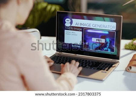 Seen from behind modern woman with laptop using text to image ai image generator in modern office. Royalty-Free Stock Photo #2317803375