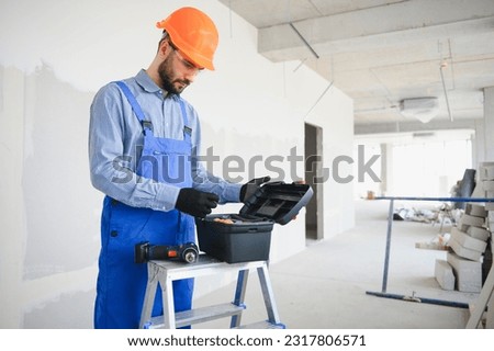 builder on construction site with tool box.