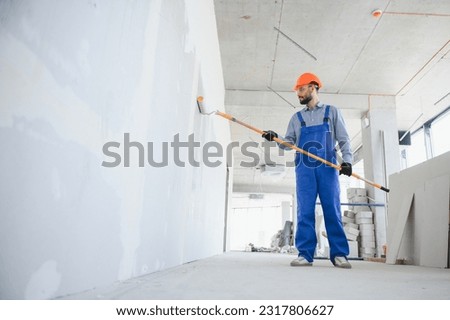 painter man painting the wall, with paint roller. Royalty-Free Stock Photo #2317806627