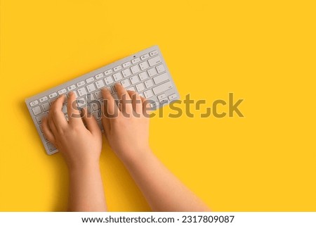 Female hands with modern computer keyboard on yellow background