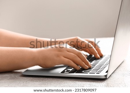Female programmer using laptop on light table, closeup