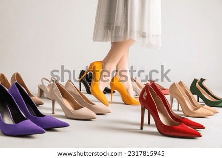 Female legs and many stylish high heels on grey background Royalty-Free Stock Photo #2317815945