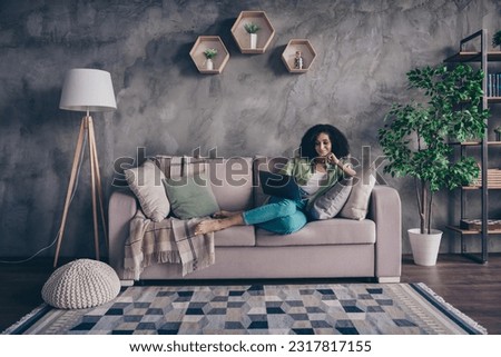 Full body photo of focused beautiful young lady lying couch comfort apartment good interior use laptop watching netflix weekend indoors
