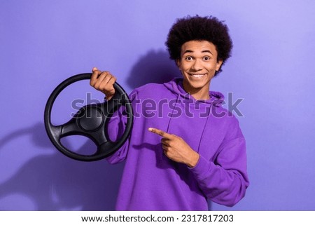 Portrait of cheerful person wear violet hoodie hold steering wheel directing at steering wheel isolated on purple color background