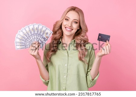 Photo of cheerful positive lady wear green shirt comparing credit card vs cash isolated pink color background