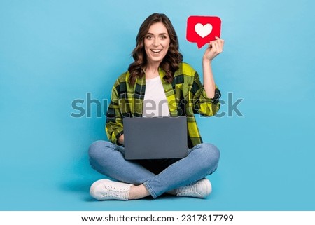 Full size photo of cheerful nice girl sit floor use netbook hold like notification card isolated on blue color background