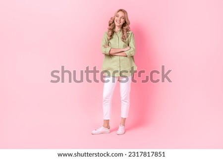 Full length photo of sweet dreamy woman dressed green shirt arms folded looking empty space isolated pink color background