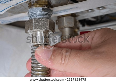 Gas leak at home boiler room. Inflating bubbles of soap mixture applied to the threaded joint on the gas flexible pipe indicate a gas leak. Preventing a gas explosion disaster. Royalty-Free Stock Photo #2317823475