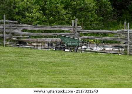 A wheelbarrow near a fence in a garden