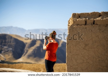 Young caucasian woman taking photos of mountains. Active lifestyle concept.