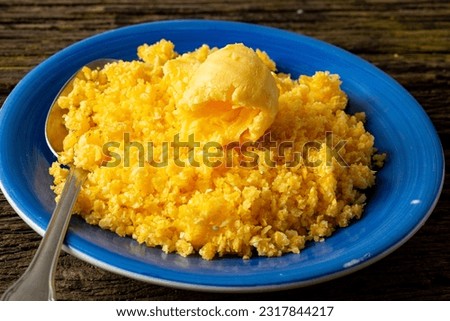 Dish of couscous "cuscuz brasil" "Cuscus,Cuzcuz,Cuscuz" with eggs and butter, from the north and northeast of Brazil, typical food of Brazilian cuisine, on a rustic wooden table typical of a farm Royalty-Free Stock Photo #2317844217