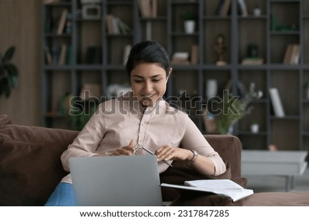 Young lady in headset take part in virtual discussion on educational video conference with teacher mates. Indian woman student speak by laptop give correct answer on coach trainer question Royalty-Free Stock Photo #2317847285