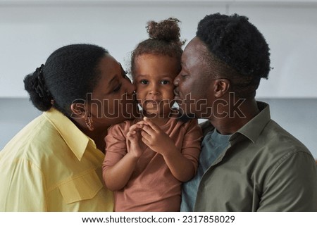 Parents kissing their little daughter Royalty-Free Stock Photo #2317858029