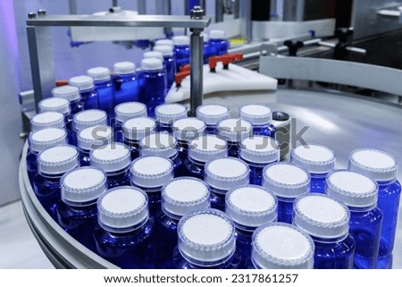 blue plastic bottle on production line of conveyor belt at filling machine in medical factory. pharmaceutical manufacturing. Royalty-Free Stock Photo #2317861257