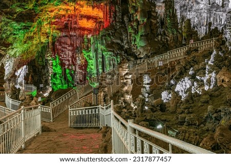 Beni Add cave, Ain Fezza, Tlemcen, Algeria. Interior view with its marvelous stalagmites and stalactites. White ramp for the pedestrian walkway path and rocks in green, orange, white and purple colors