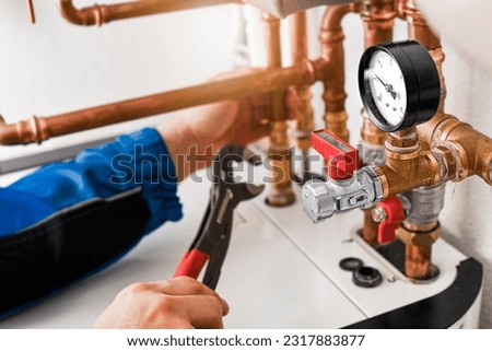 Plumbing concept or service water worker. copper pipeline of a heating system in technical room. Boiler and expansion expansion tank system, detail of pressure gauge. Royalty-Free Stock Photo #2317883877