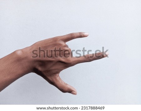 Man's hand gesturing rock and roll, heavy metal, devil horns gesture or I love you on white background. Copy space.