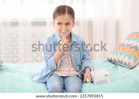 Sick little girl using nebulizer for inhalation on bed at home Royalty-Free Stock Photo #2317892815