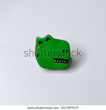 Handmade Rex clay pin isolated on white background. Clay broach. Art. Toy Story.