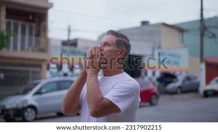 Religious Senior man standing on street in Prayer. Devoted middle-age male caucasian person Praying to God looking at sky smiling exuding HOPE and FAITH Royalty-Free Stock Photo #2317902215