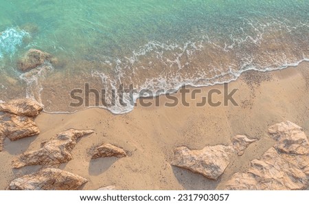 Sand beach top view seaside with white foamy and blue sea on daylight, seashore and space for text presentation on summer tourism tropical hi season  