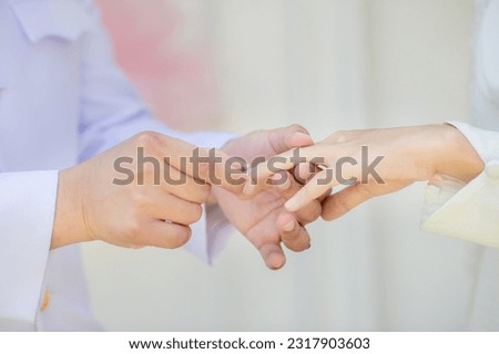 muslim groom in white dress wear wedding rings to left ring finger of muslim bride.concept for wedding card background, poster,Invitation card Royalty-Free Stock Photo #2317903603
