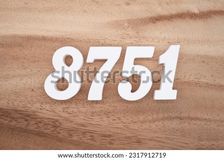 White number 8751 on a brown and light brown wooden background.