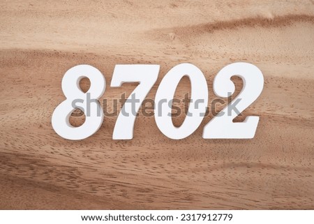 White number 8702 on a brown and light brown wooden background.