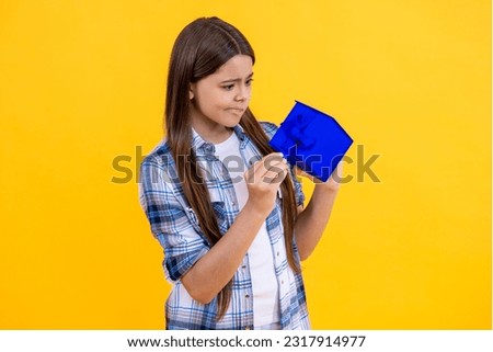 curious teen girl with birthday gift isolated on yellow. teen girl celebrating birthday with present in studio. teen girl holding birthday present box on background. birthday teen girl posing