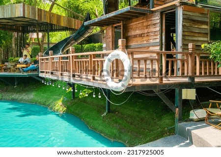 Beautiful two story waterfront house,colorful landscaping and lush green grass in tropical climate,wooden house by the lake,view of the lake in the forest,green lake landscape in nature.
