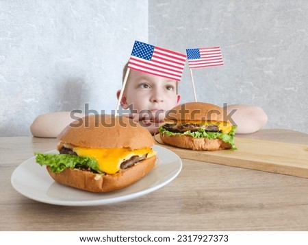 USA Independence Day. USA Independence Day celebration. American flag burgers. The boy eats a burger prepared for the independence day of the USA, 4th july bbq party
