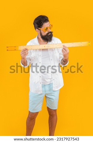 image of man hold measuring ruler. man hold measuring ruler isolated on yellow.