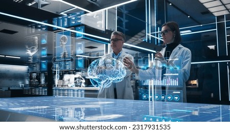 Two Neuroscientists Working With Computer-Powered VFX Hologram Of Human Brain And Nervous System In Futuristic Laboratory. Caucasian Man And Woman Working On Solutions for Brain Damage Or Trumor